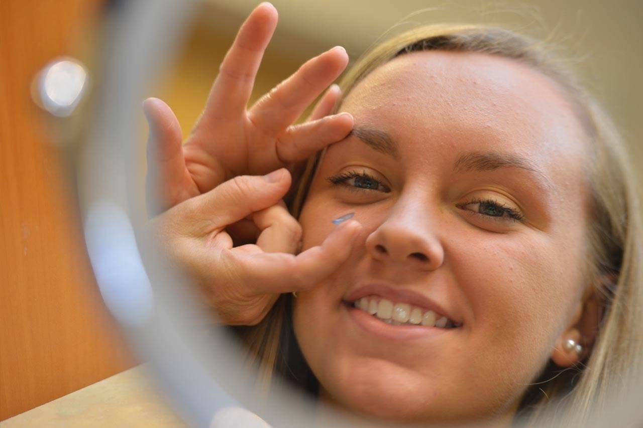 girl trying on contacts in mirror
